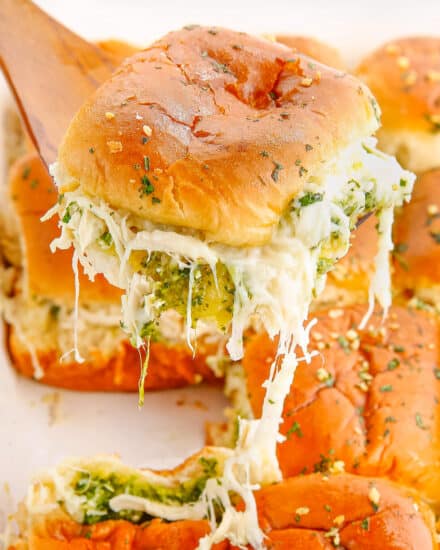 These Cheesy Garlic Pesto Chicken Sliders are gooey, hot, and so easy to make. Made with just 7 simple ingredients, with make ahead and freezer directions, they're the ultimate delicious party food! #sliders #pesto #chicken