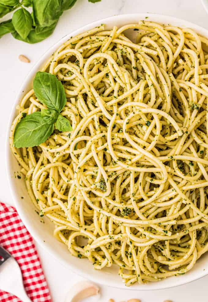 pesto spaghetti in white bowl garnished with basil