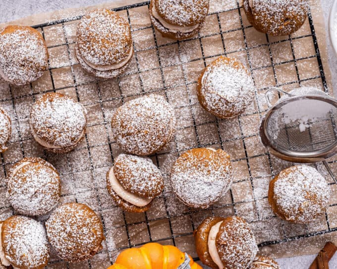 pumpkin whoopie pies on cooling rack dusted with powdered sugar