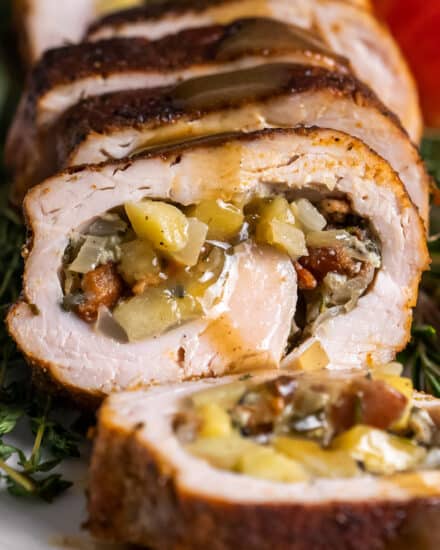 This Stuffed Pork Tenderloin with Apple Bourbon Gravy is the perfect alternative to a huge turkey on your holiday menu! Juicy pork wrapped around a sweet and savory filling made from apples, onions, bacon and herbs, roasted, then smothered in an apple cider bourbon gravy that is out of this world delicious. #pork #tenderloin #holiday #stuffed