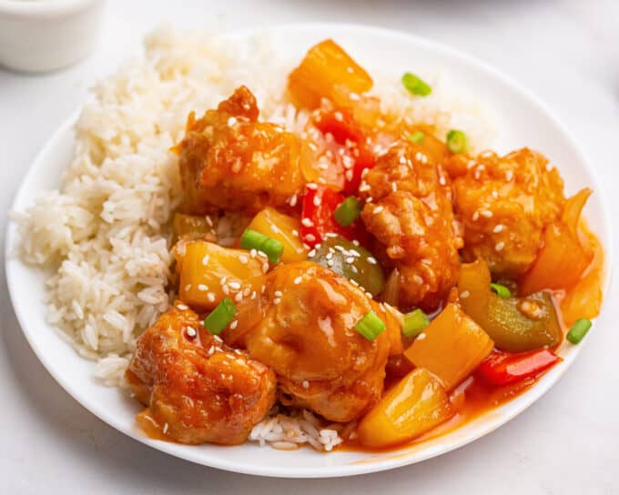 white plate full of white rice and sweet and sour chicken