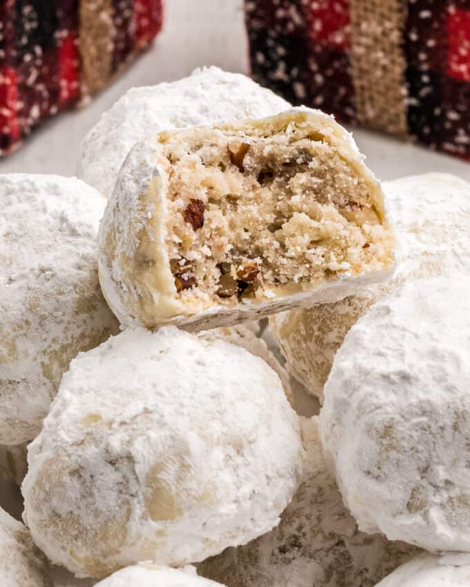 stack of snowball cookies with the top cookie bitten in half to show the inside