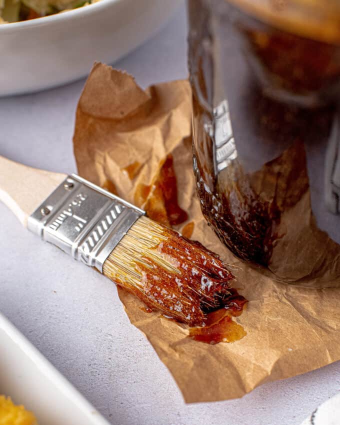 basting brush with whiskey glaze on brown paper next to a mason jar