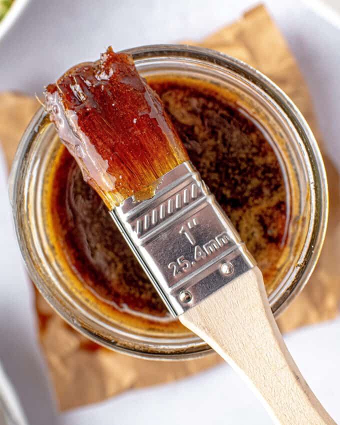 basting brush laying on top of a jar filled with whiskey glaze