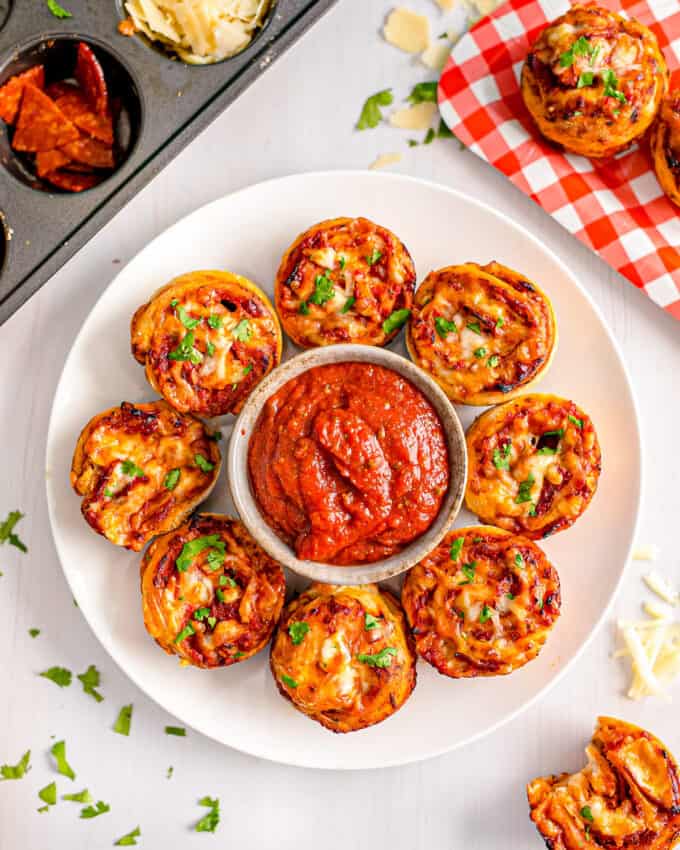 ring of pizza pinwheels on plate with a bowl of pizza sauce