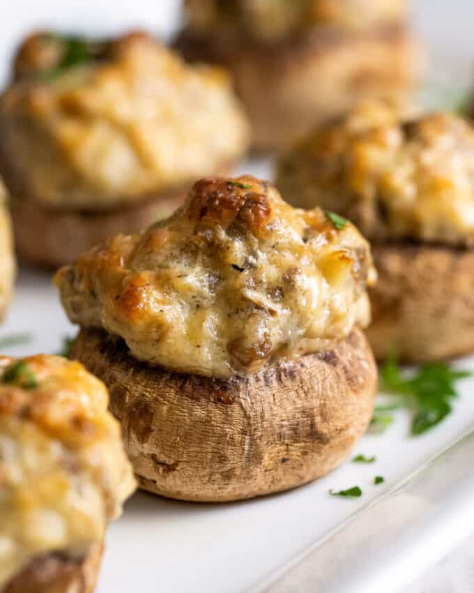 line of sausage stuffed mushrooms on white platter