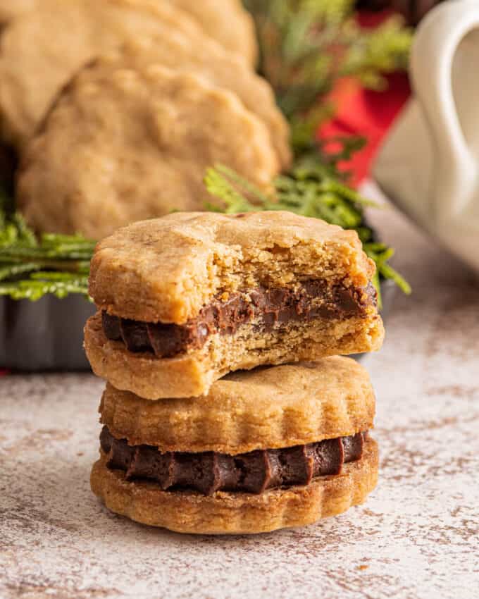 two shortbread sandwich cookies stacked on top of one another with the top one with a bite taken out of it
