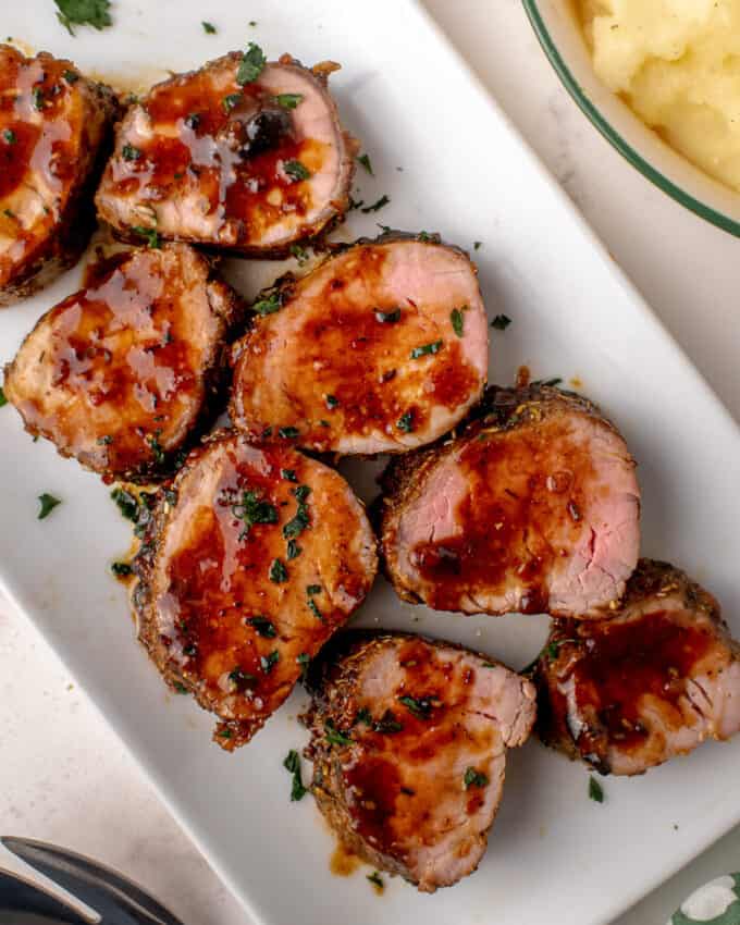 slices of pork tenderloin on platter with sauce drizzled over the top