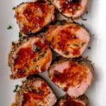 slices of pork tenderloin with glaze on white plate