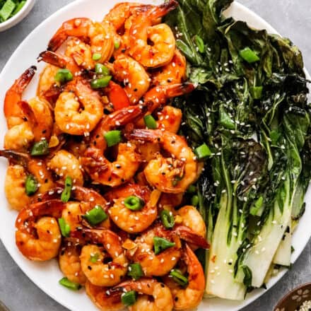 white plate with chili garlic shrimp on one half and bok choy on the other