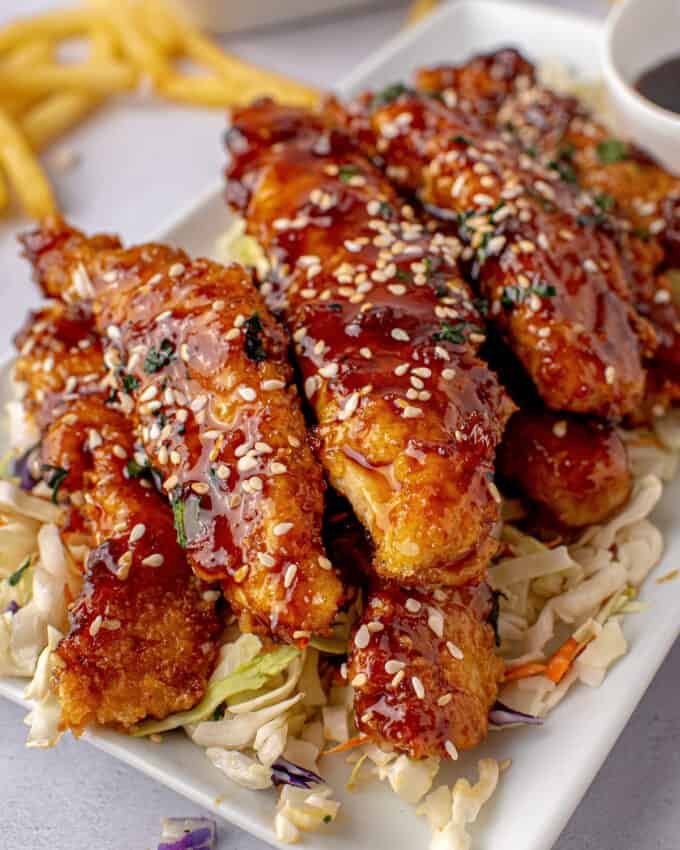 sesame jack chicken strips on plate with extra sauce