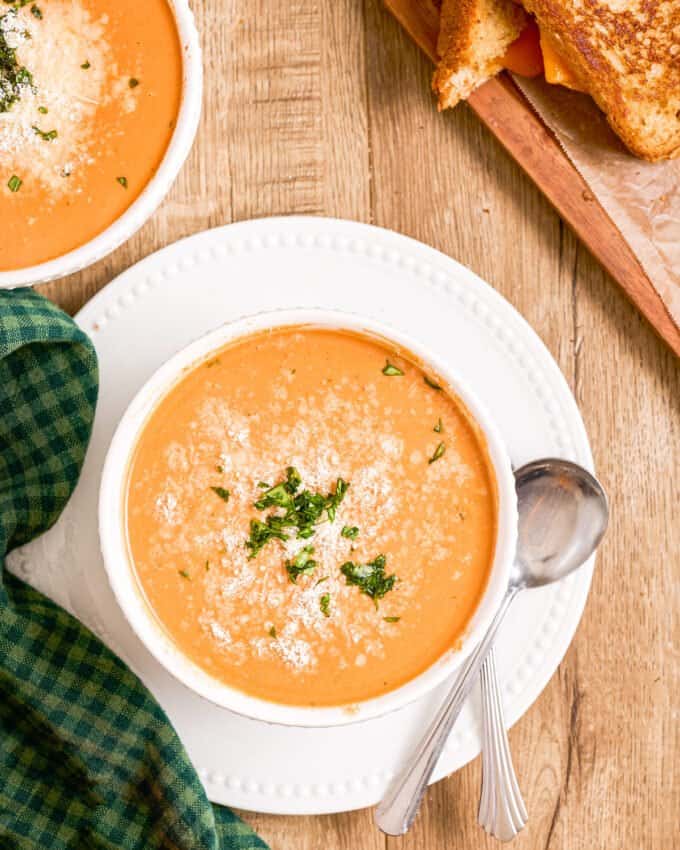 bowls of tomato soup with kitchen towel and grilled cheese sandwiches