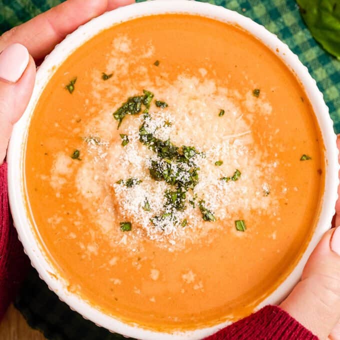 bowl of creamy tomato basil soup with Parmesan cheese and basil