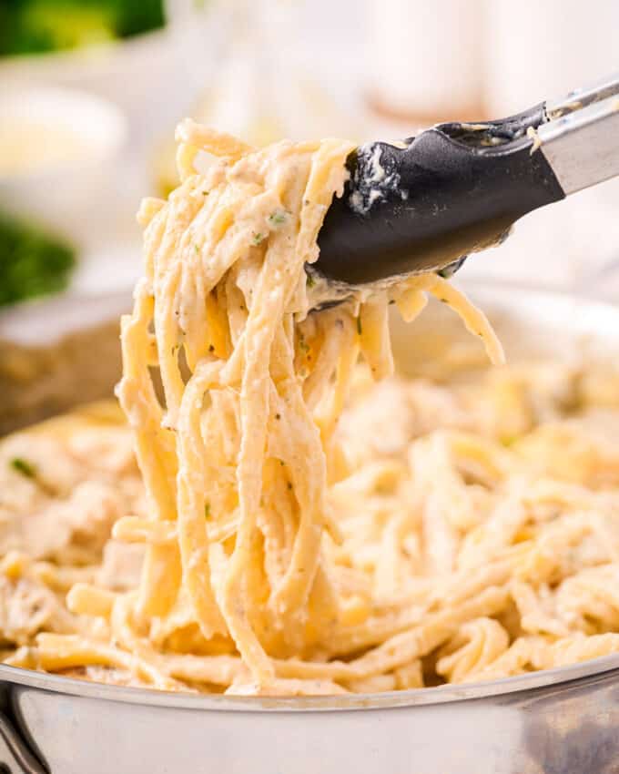 tongs pulling creamy fettuccine alfredo