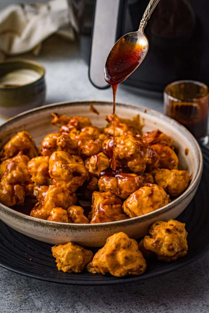 drizzling honey chipotle sauce over cauliflower bites