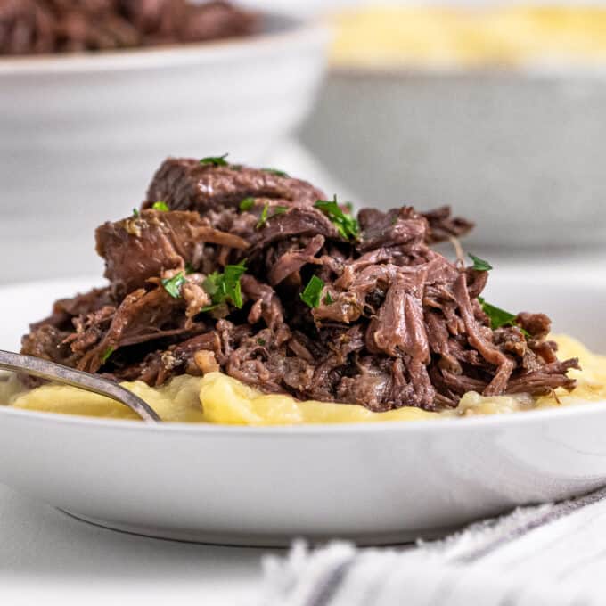 This Mississippi Pot Roast is made with no packets (from scratch), and is deliciously savory, buttery, and has the most beautiful tangy kick from the pepperoncini peppers! Made in the slow cooker or Instant Pot, it's a perfect family meal everyone will love. Great with mashed potatoes, in sandwiches, and more! #potroast #mississippi #beef #slowcooker