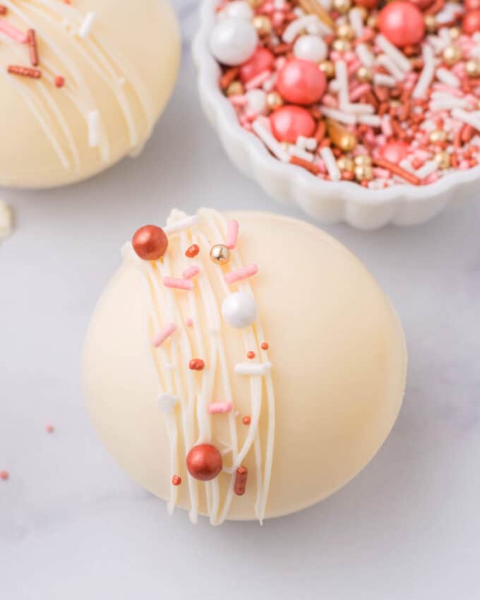 white chocolate hot cocoa bombs with bowl of sprinkles