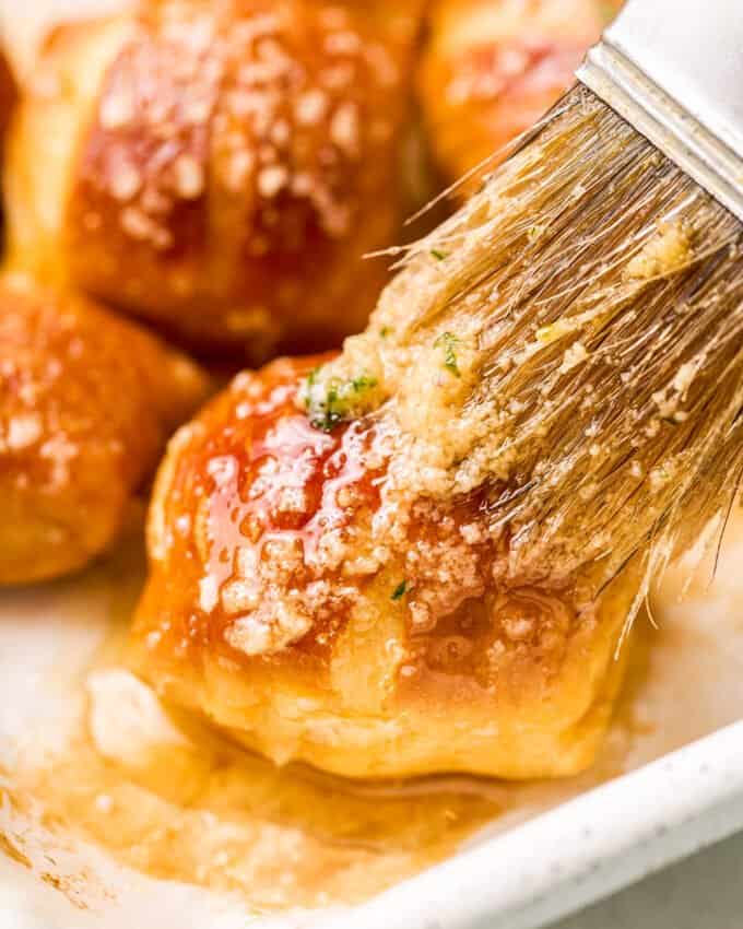 brushing garlic butter onto soft pretzel bite