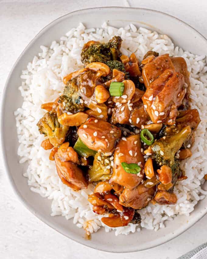 cashew chicken on a bed of white rice on white plate