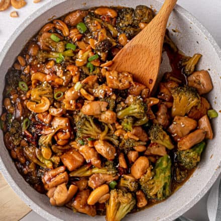 cashew chicken in skillet with a wooden spoon