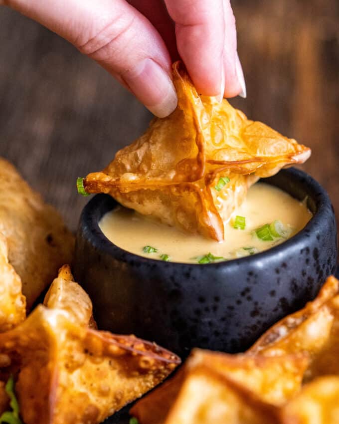 dipping crab rangoon into mustard sauce