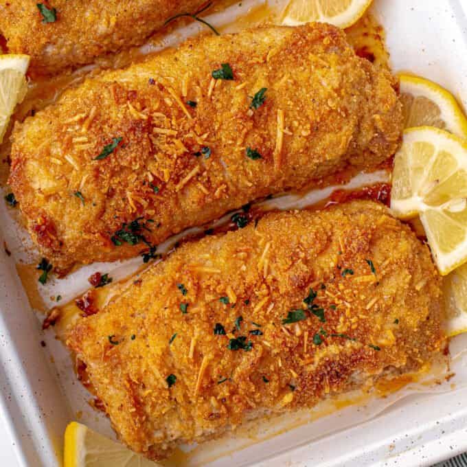 breaded pork chops on baking sheet with lemons