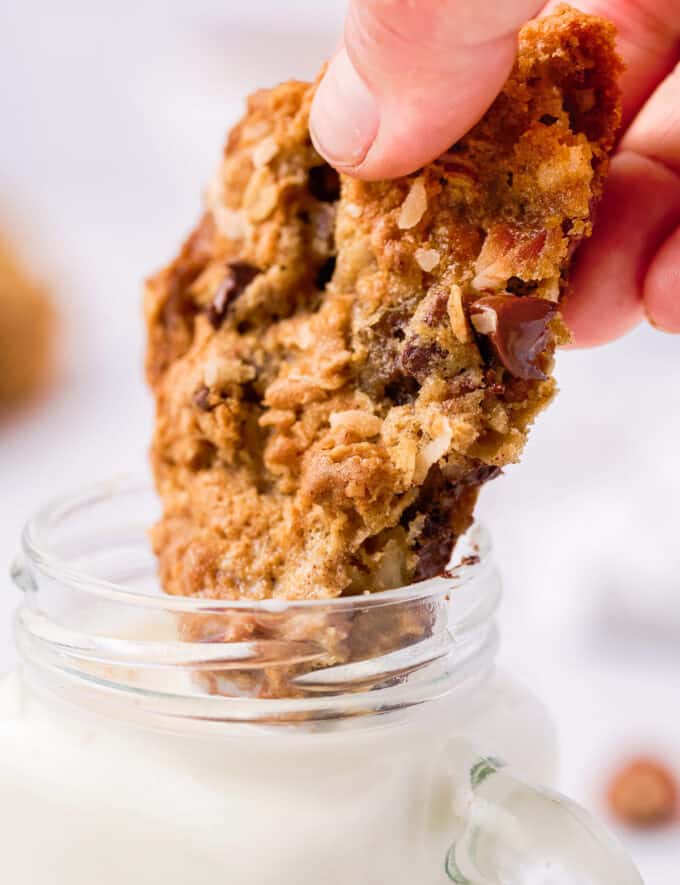 dipping half a cowboy cookie in a glass of milk