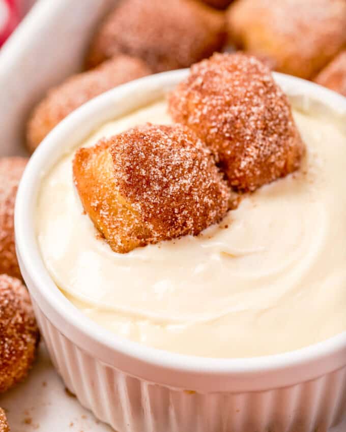 ramekin of sweet cream cheese dip with two pretzel bites dipped in it