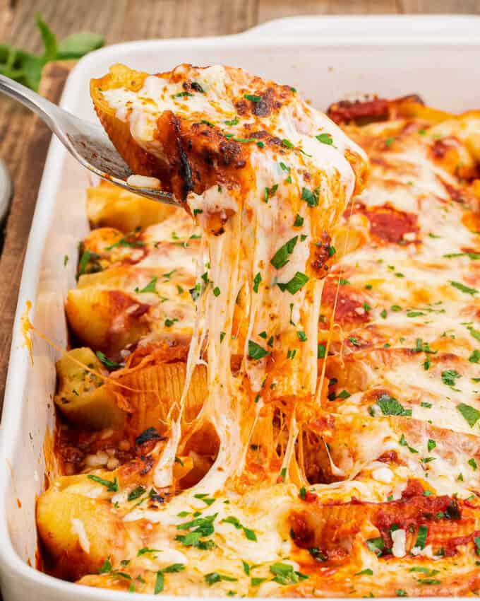 spoon scooping a stuffed shell out of the baking dish