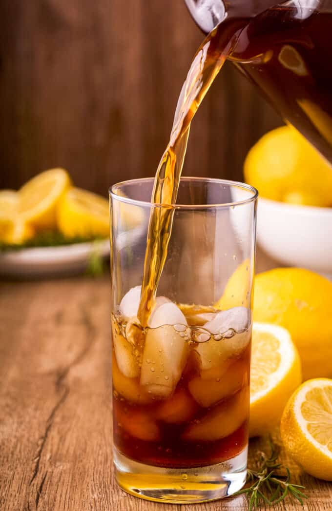 pouring iced tea into a tall glass with ice