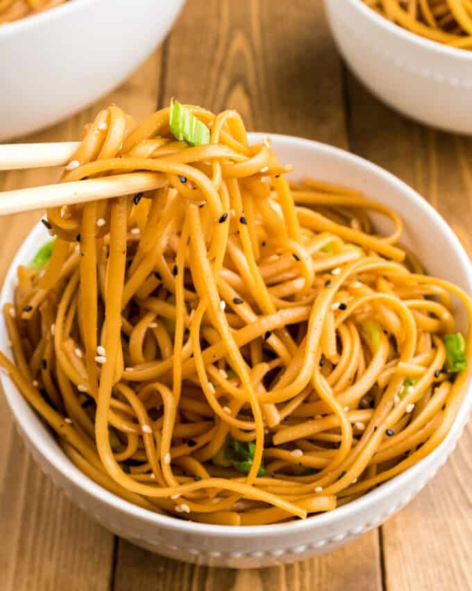 chopsticks holding bunch of sesame noodles