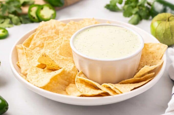 platter of tortilla chips and small white bowl of jalapeño dip