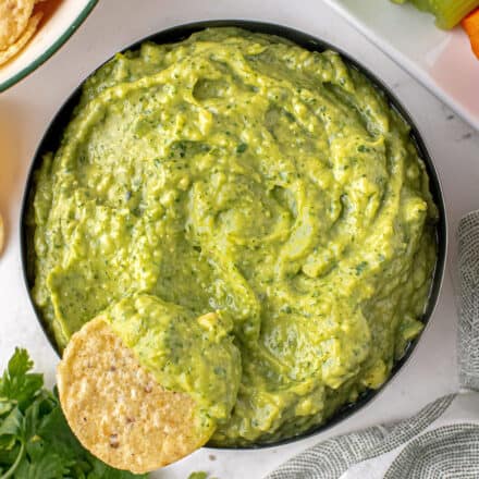 bowl of avocado dip with a tortilla chip dipped in it