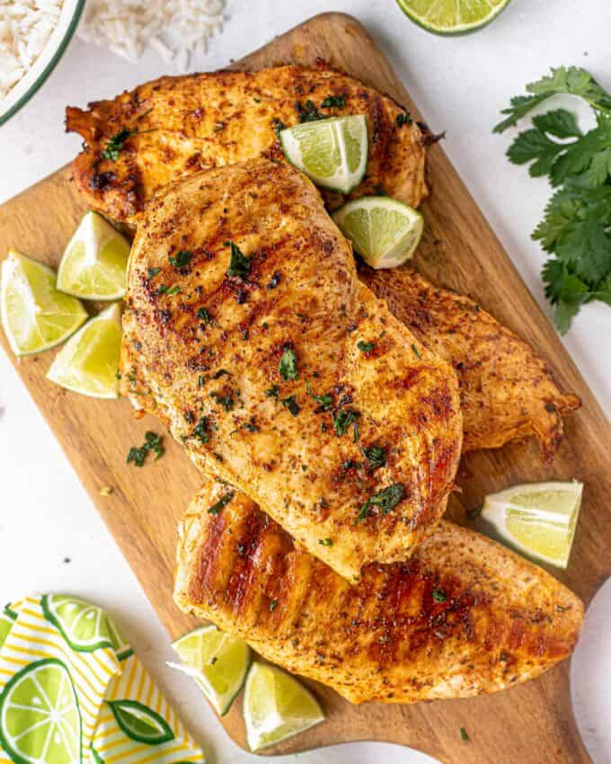 grilled chicken on wooden cutting board with lime wedges