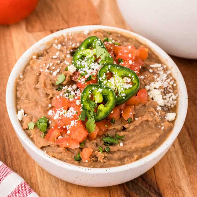 bowl of refried beans with jalapenos and tomatoes