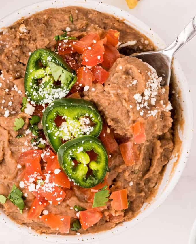 serving a spoonful of refried beans from white bowl