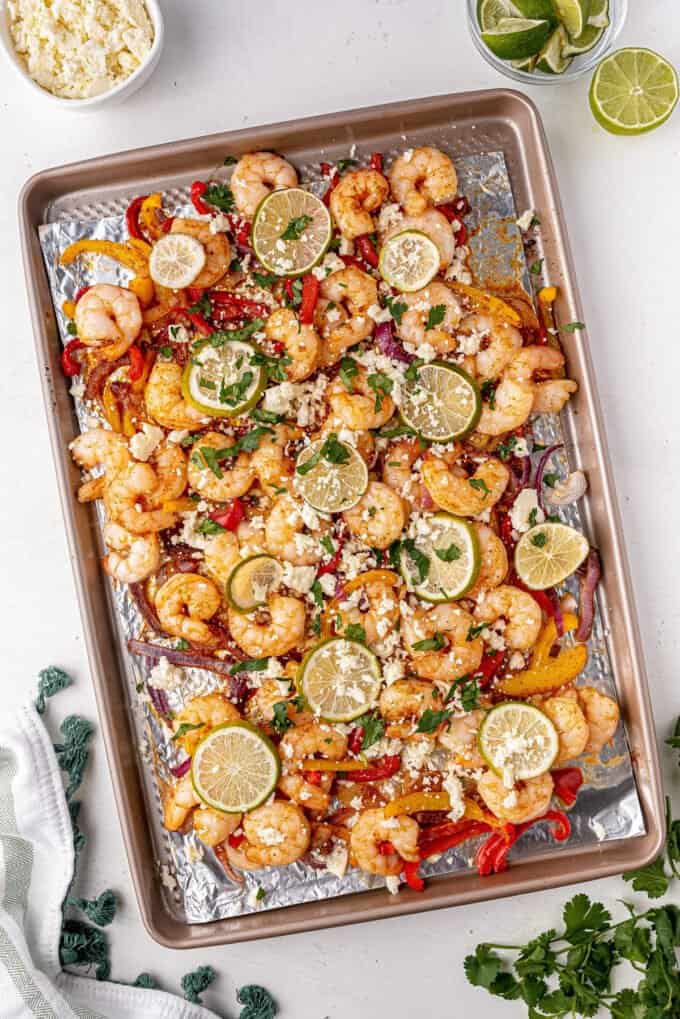shrimp fajitas on sheet pan with cotija cheese and lime slices