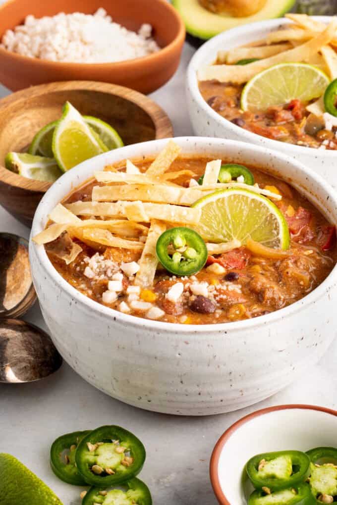 white bowl of lentil tortilla soup garnished with lime 