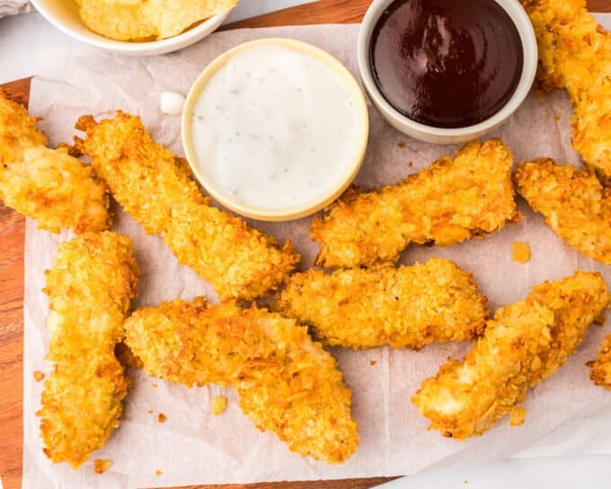 air fryer chicken tenders on parchment paper with two dipping sauces