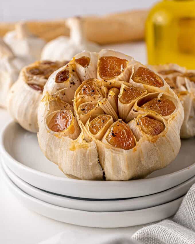 heads of roasted garlic on stack of white plates