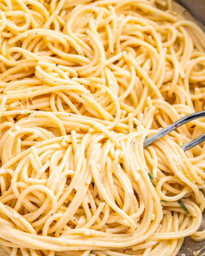 serving tongs grabbing a pile of creamy lemon pasta