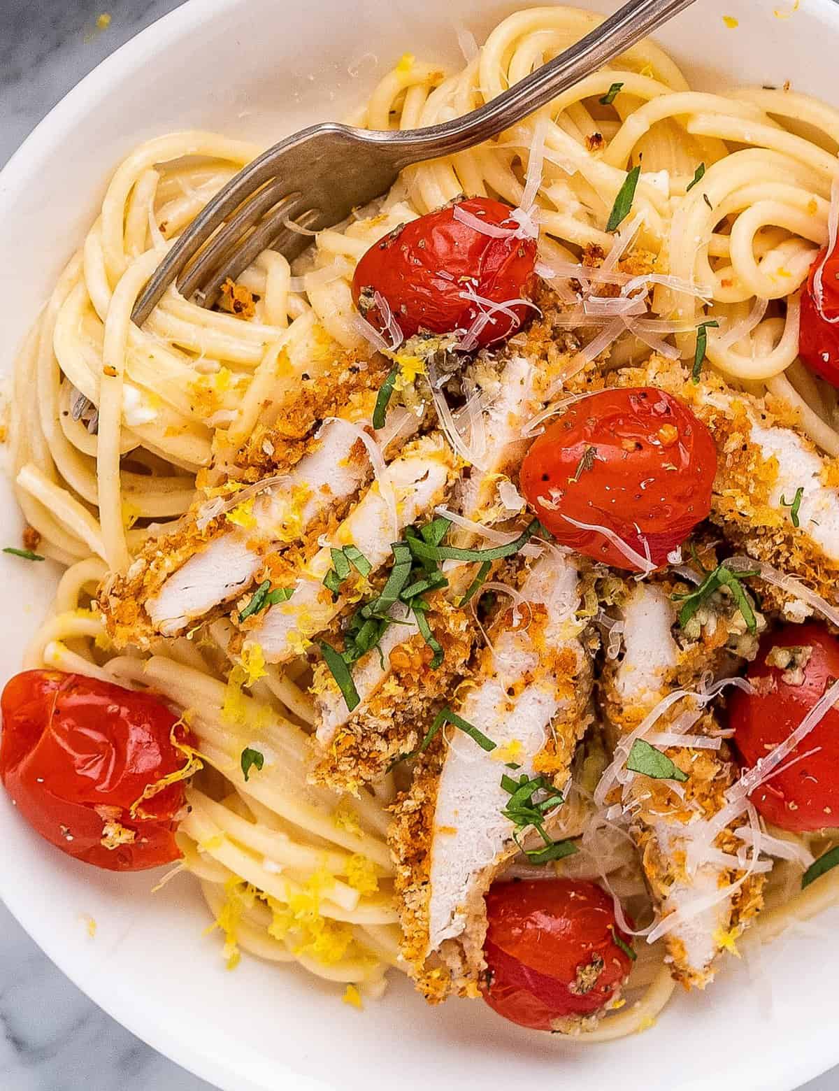 This creamy lemon chicken pasta combines bright and tangy creamy pasta, crunchy baked chicken cutlets, garlicky burst cherry tomatoes, and savory Parmesan cheese. It's a great weeknight-friendly dinner idea that the whole family will love!