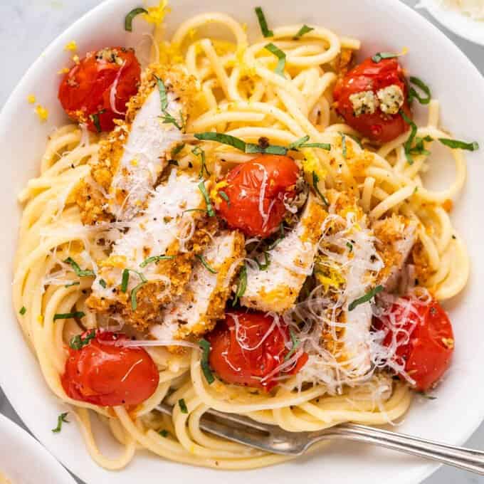 white bowl of lemon chicken pasta with cherry tomatoes
