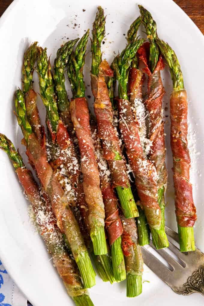 air fryer asparagus wrapped in prosciutto on white platter