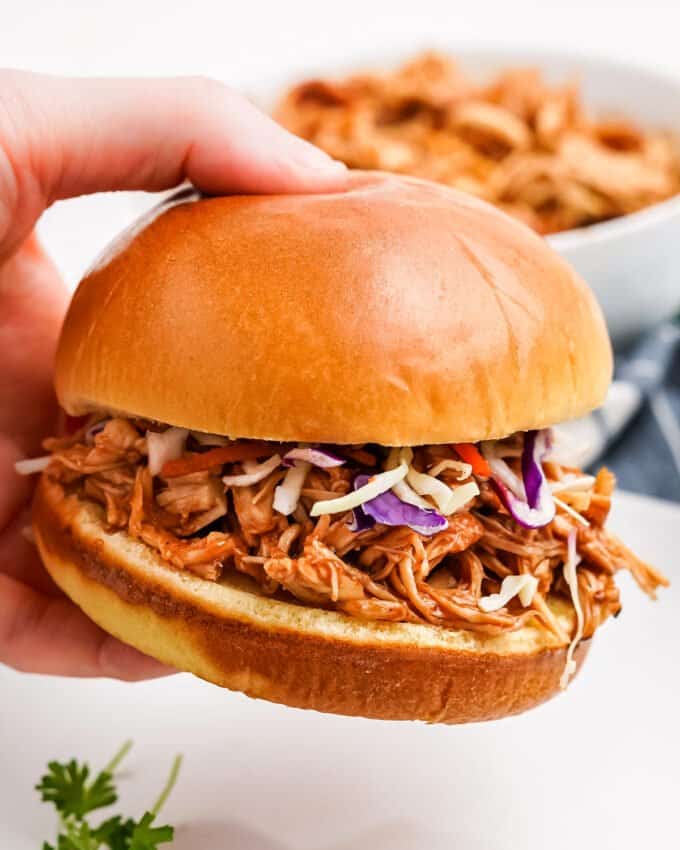 holding a bbq chicken sandwich with coleslaw