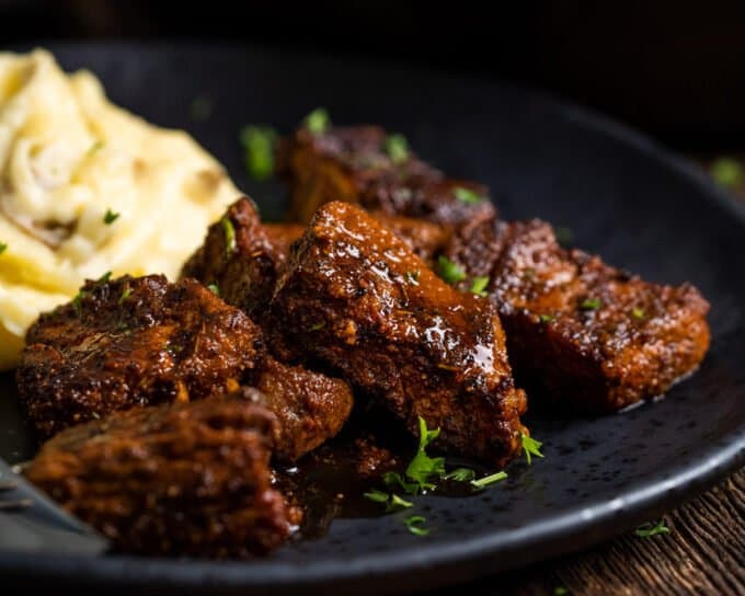 steak bites on black plate with mashed potatoes