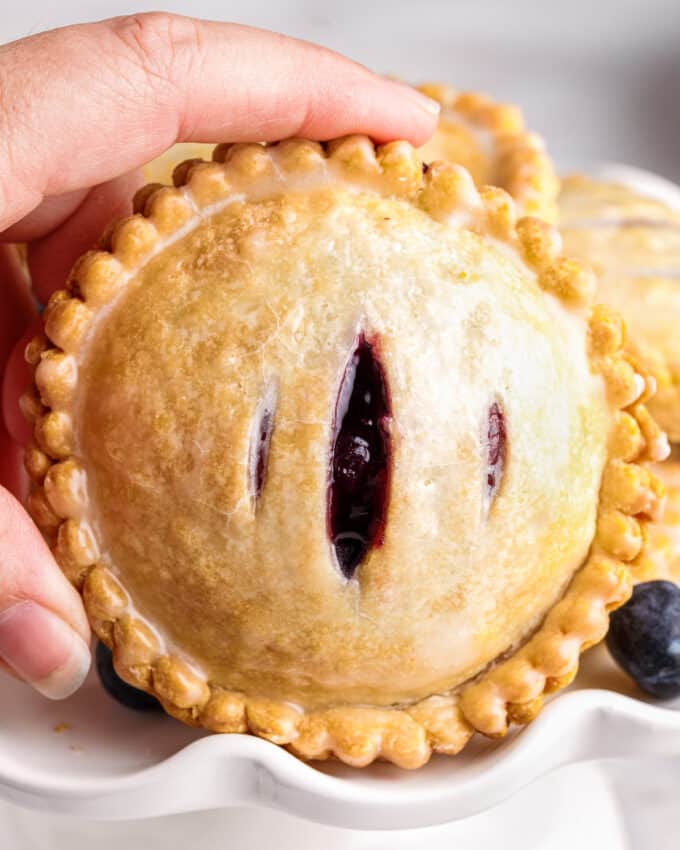 holding a hand pie filled with blueberry filling and cheesecake