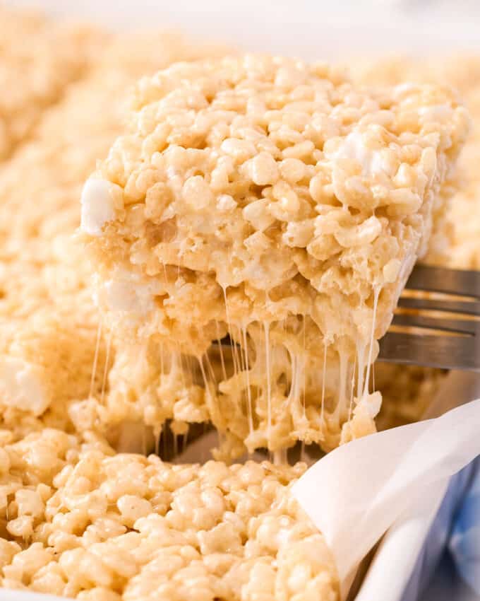 using a spatula to take a rice krispie treat out of the baking dish