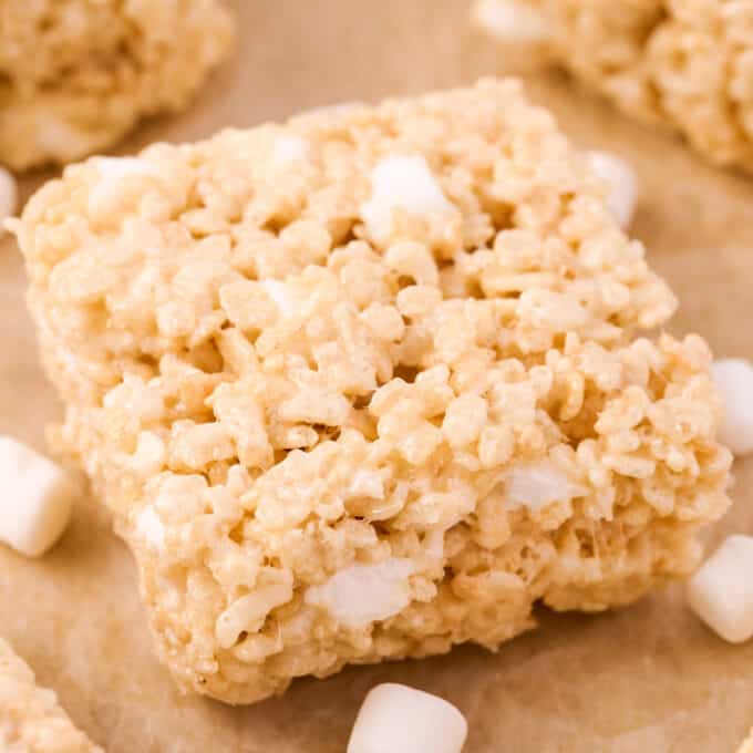 rice krispie treat on parchment paper surrounded by other treats and marshmallows