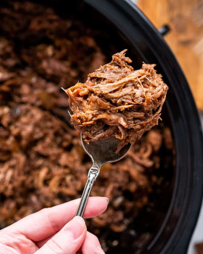 pulled pork on a serving fork over the slow cooker